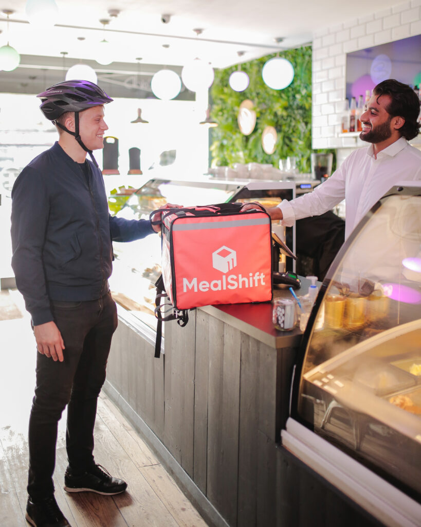 MealShift driver handing a branded delivery bag to a restaurant owner